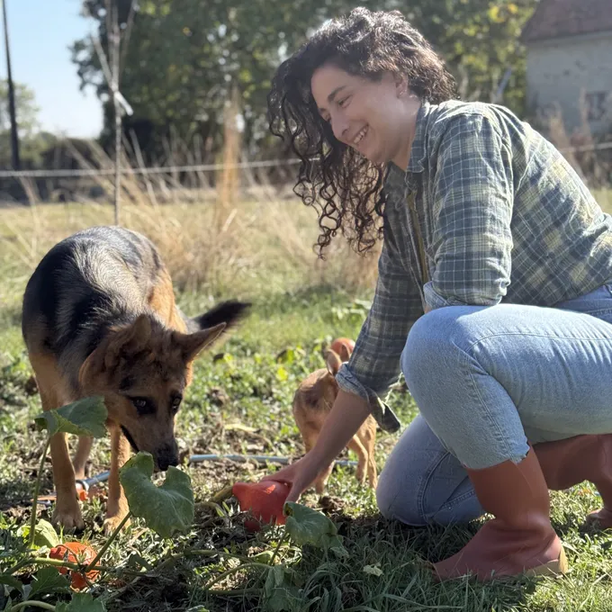 Isadora VUONG VAN accroupie dans le potager avec ses deux chiennes